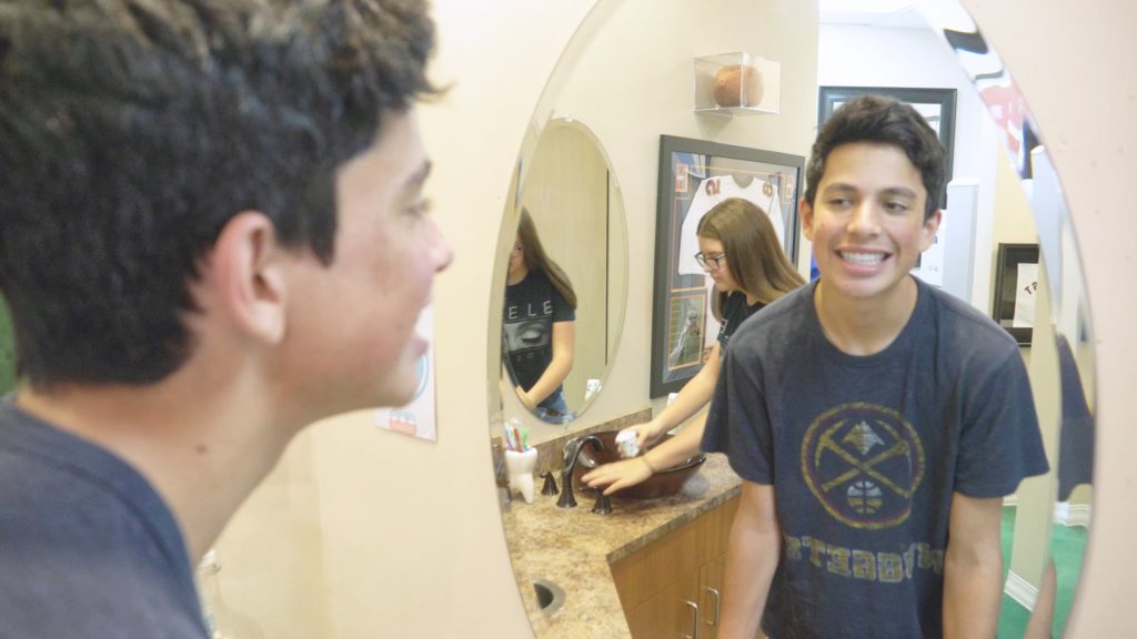 Teen patient looking at their teeth in the mirror